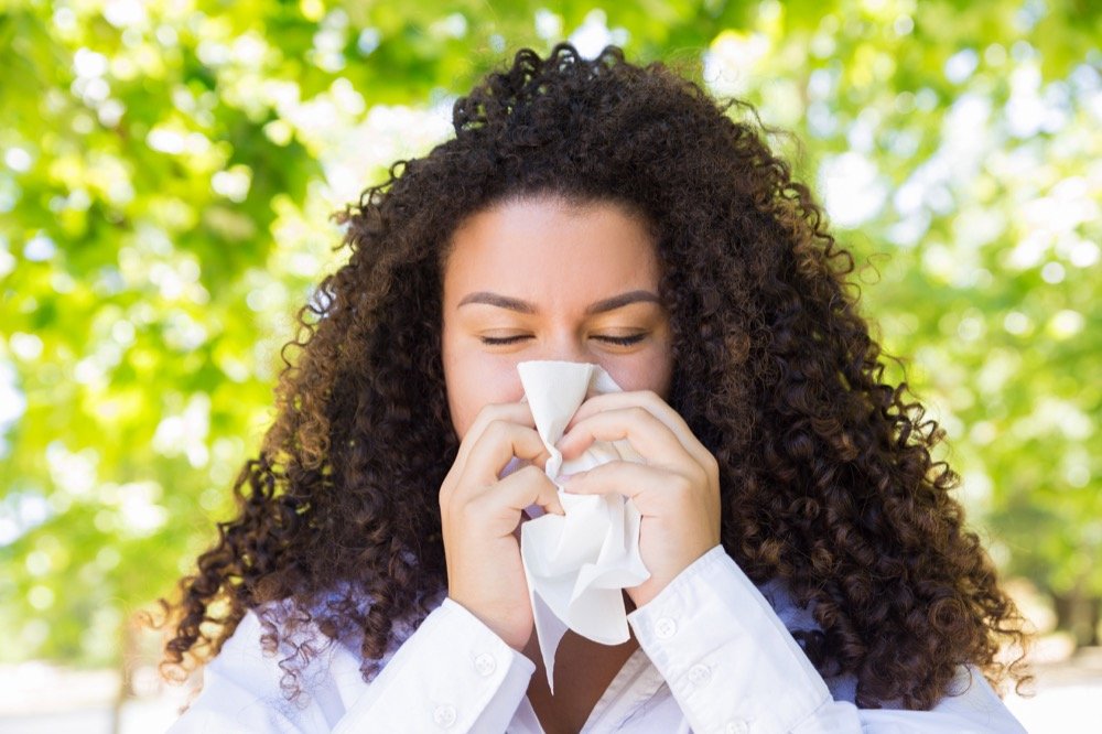 jeune femme en état allergique se mouche